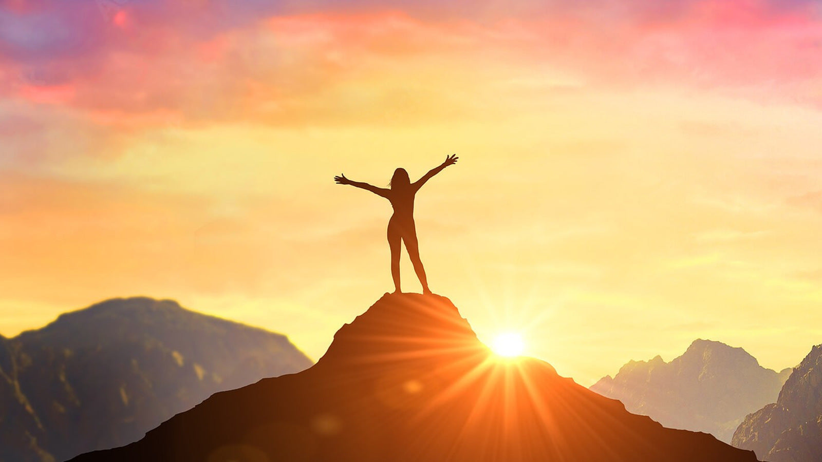 A figure standing on a mountain at sunrise